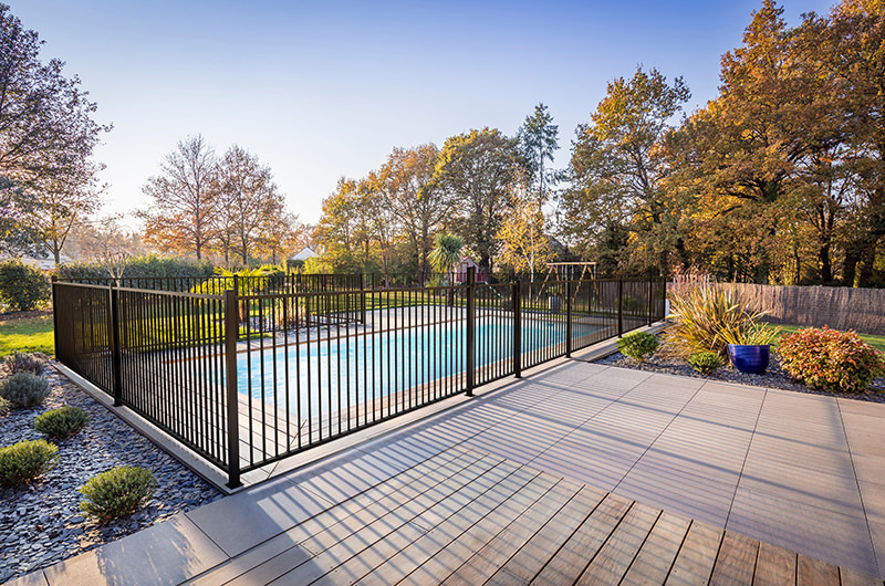 stock photo of black metal fencing around pool at residential home on Axiom Built's website